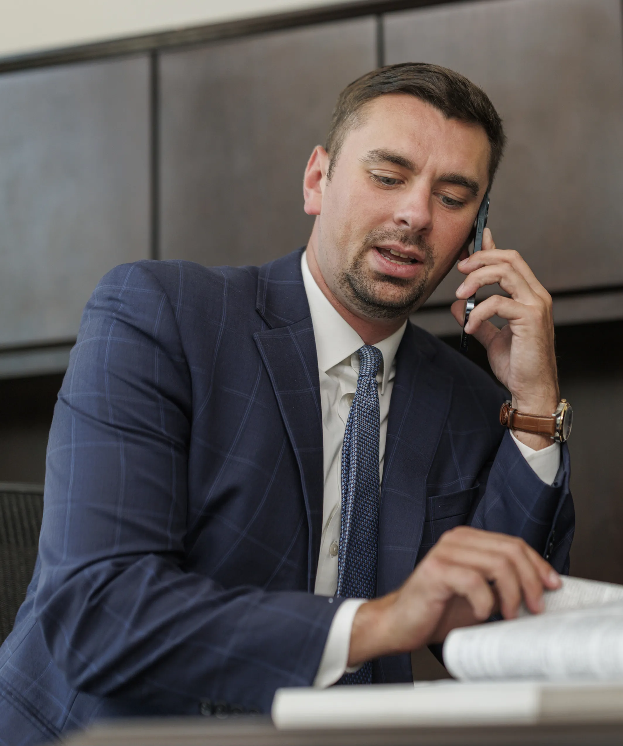 man in suit talking with someon on call on the desk with some files open and hands shuffling the files and one hand on phone with ear main in suit talking with someon on call on the desk with some files open and hands shuffling the files and one hand on phone with ear